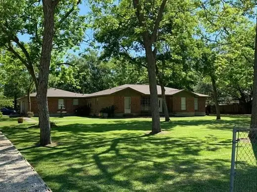 Spacious green yard with trees at Primary Purpose House, a sober living home in Galveston.